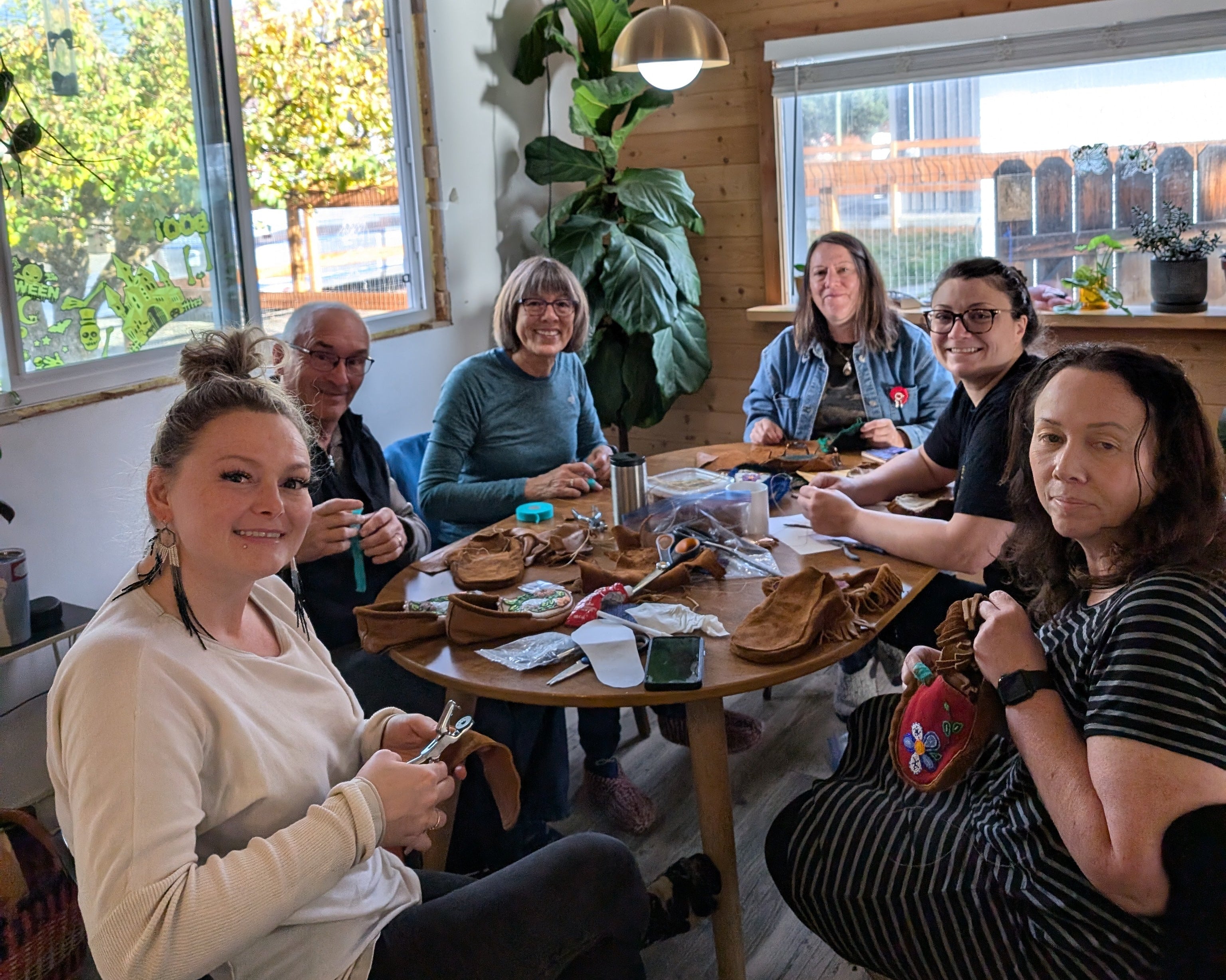 Group of people sitting around a table in a room with large windows and decorative elements.
